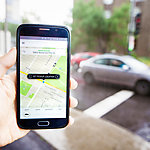 View of a hand holding a phone and ordering an Uber taxi ride. 