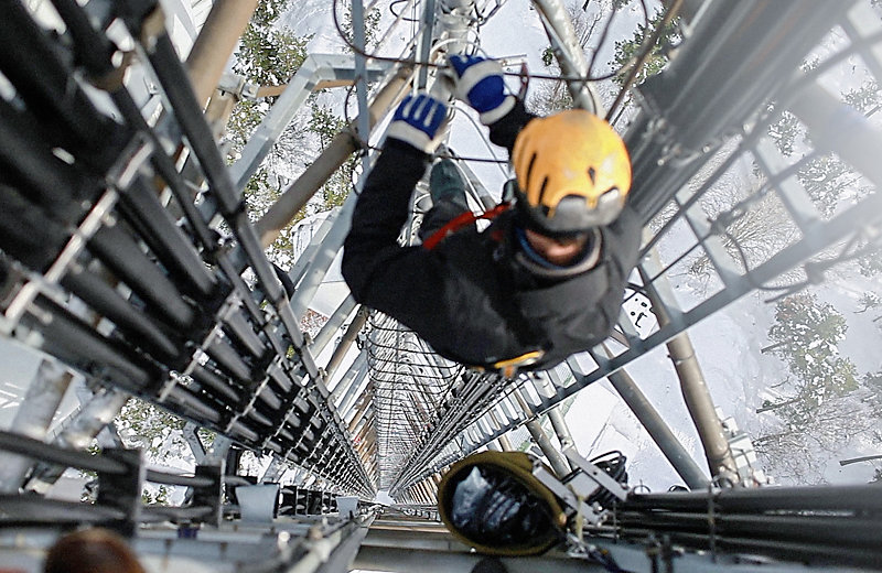 Worker on top of a very high transmission tower repairing the antenna.