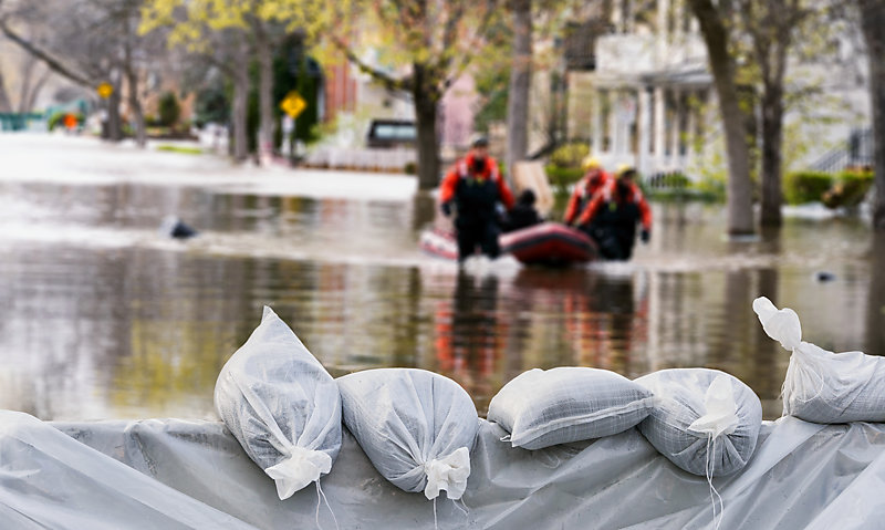 Sandbags used as flood protection, with flooded homes in the background.