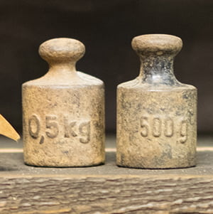 Close up of three old weights on wooden background.
