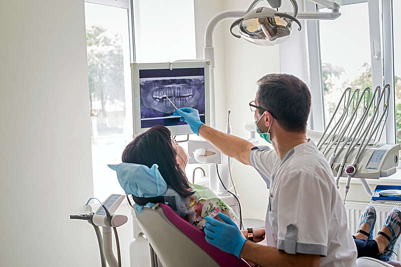 Dentist showing patient's teeth on X-ray.