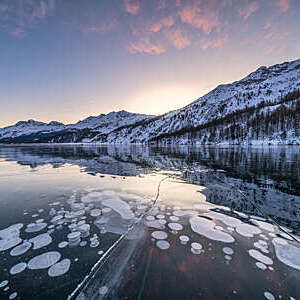 Frozen lake Sils with trapped ice bubbles and Piz Corvatsch in background, canton of Graubunden, Engadine, Switzerland