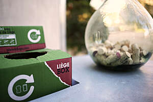 Two green carboard boxes and a glass jar containing wine bottle corks.