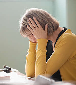 Overworked teacher is sitting by her desk.