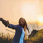 A personal perspective of a smiling happy woman leading and pulling someone excitedly towards Victoria Falls Zimbabwe Southern Africa at sunrise